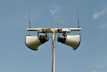 Metal Horns on Public Address System on Pole seen against Blue Sky 