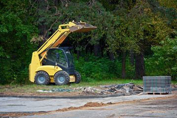 Sidewalk paving work, paving slabs pallet and small loader. Paving road with paving slabs in park....