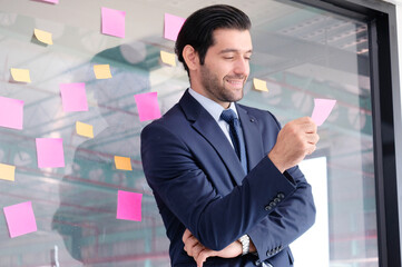 Smiling young businessman holding notepad.