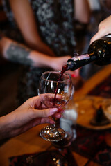 Pours wine in glass. Tasting tour in Armenia. Hand holding wineglass. Alcohol is poured from a bottle,  tourists on background, gastronomic