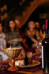 Wine tasting in Armenia. Tourists people on background. Cheese plate for a snack and bottle of wine. Wicker stand