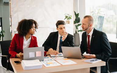 Happy businesspeople while collaborating on a new project in an office. Group of diverse businesspeople using a laptop and tablet in office..