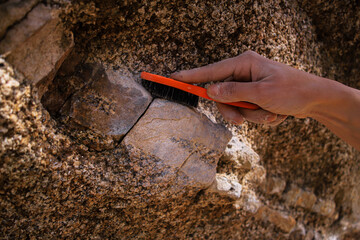 A person using a brush to clean a rock. Motif Climbing