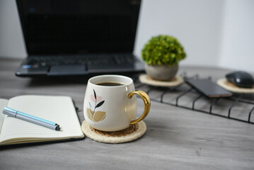 Working space at home, laptop, coffee mug and papers on wooden background