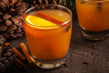 Two glasses of Mulled Wassail Cider with apple cider, cinnamon, cloves, orange, apple, lemon, and fresh ginger horizontal shot with fruit in the background