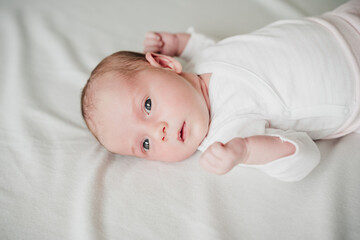 cute newborn baby girl resting on bed at home during daytime. Family