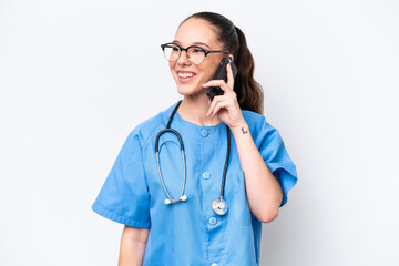 Young caucasian surgeon doctor woman isolated on white background keeping a conversation with the mobile phone