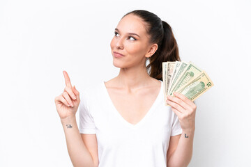 Young caucasian woman taking a lot of money isolated on white background pointing up a great idea