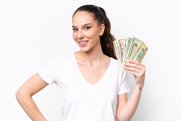 Young caucasian woman taking a lot of money isolated on white background posing with arms at hip and smiling