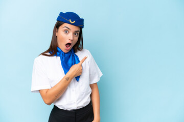 Airplane stewardess caucasian woman isolated on blue background surprised and pointing side