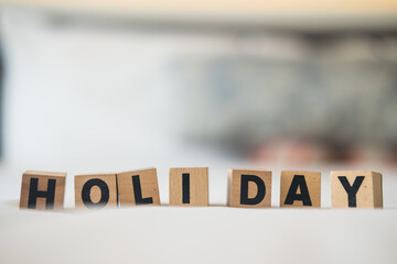 HOLIDAY word made with wood building blocks on white bed. Close up
