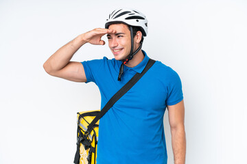 Young caucasian man with thermal backpack isolated on white background looking far away with hand to look something