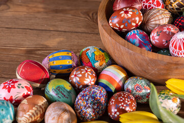 Easter eggs lie in a bowl and on a wooden table. Top view of the composition.