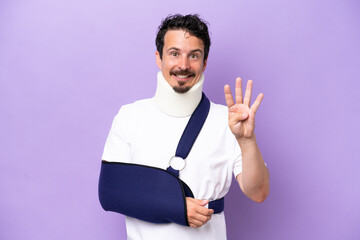 Young caucasian man wearing a sling and neck brace isolated on purple background happy and counting...