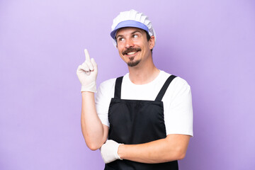 Fishmonger man wearing an apron isolated on purple background pointing up a great idea
