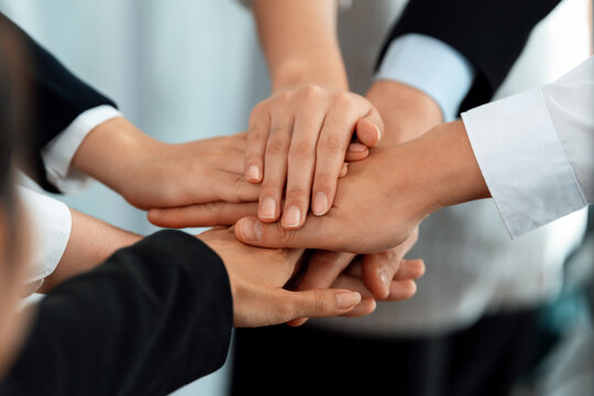 Top view closeup business team of suit-clad businesspeople join hand stack together. Colleague collaborate and work together to promote harmony and teamwork concept in office workplace.