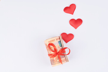 Russian rubles on white background, bundle of five thousand banknotes with red ribbon in heart box, money gift concept