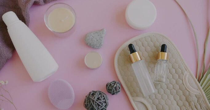 Top view of bottles with cosmetic products and sponges for skincare massage on yellow background. Cosmetology and spa produce concept.