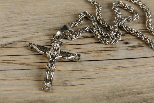 Close up of silver Crucific necklace isolated on wooden background