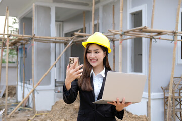 Industrial woman engineer in a factory using laptop and smartphone.