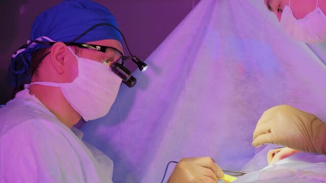 Two Surgical Doctors Wearing Masks Are Using Specialized Equipment For Soft Tissue Cauterization During An Operation. Slow Motion.