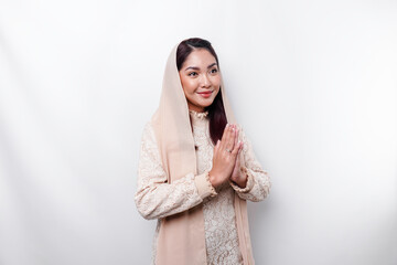 Fototapeta premium Portrait of a young beautiful Asian Muslim woman wearing a headscarf gesturing Eid Mubarak greeting