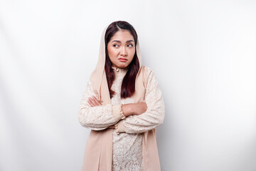 Fototapeta premium A thoughtful young Asian Muslim woman wearing headscarf while looking aside, isolated by a white background