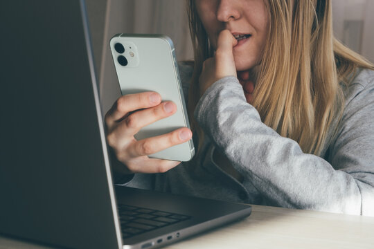 Cropped portrait of female blogger biting fingers nervous using mobile phone. Panic, shock, bulling concept. High quality toned photo about technology and security. 