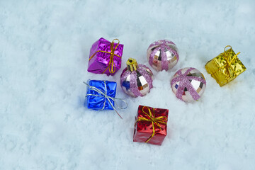 Glittered Christmas baubles with colorful presents with metallic strings