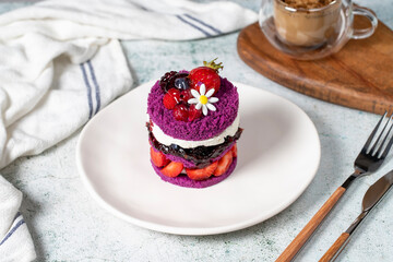 Layered fruit cake. Cake with strawberries, raspberry sauce and cream on a stone background. Patisserie desserts