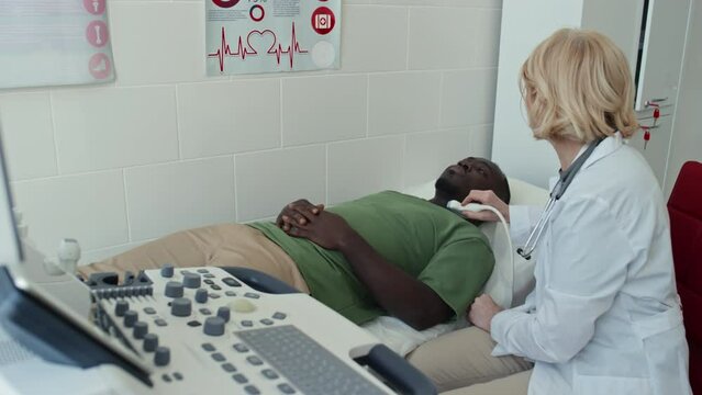 High angle shot of young Black man with hypothyroidism getting ultrasonography examination