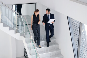 Young businessmen and female employees walking inside the office.