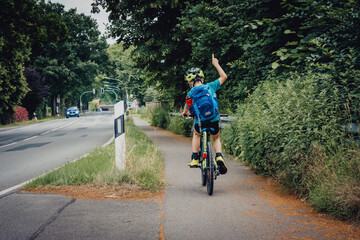Kleiner Junge in Siegerpose nach Ortsschild-Sprint während einer Fahrradtour, Niedersachsen,...