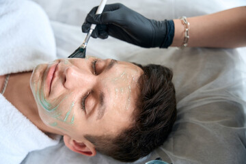 Obraz na płótnie Canvas Woman apply revitalizing mask for face on man skin