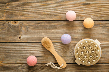 Massage bamboo brushes and bath bombs on a wooden background, top view, copy space.