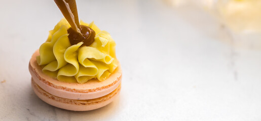 the pastry chef squeezes the filling onto macarons cookies. close-up. home bakery concept.