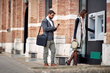 Businessman and woman takes mony from ATM