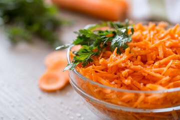 Bowl with fresh grated carrot and oil.