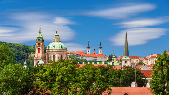 Prague historical center old skyline with Church of Saint Nicholas beautiful baroque dome and clock tower among trees