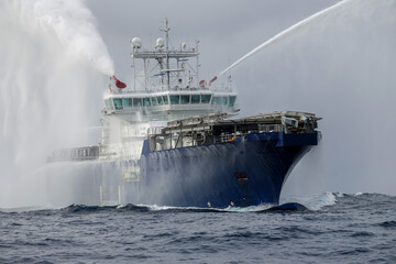 Tugboat demonstrating water discharge. A Rescue fireboat casting water stream at open water. Fire...