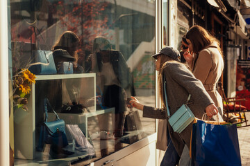 A lovely girl in gray outfit pointing at a handbag on the shop window
