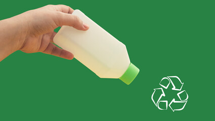 Hand with a plastic bottle, invites to recycle, green color background and blank recycling sign.