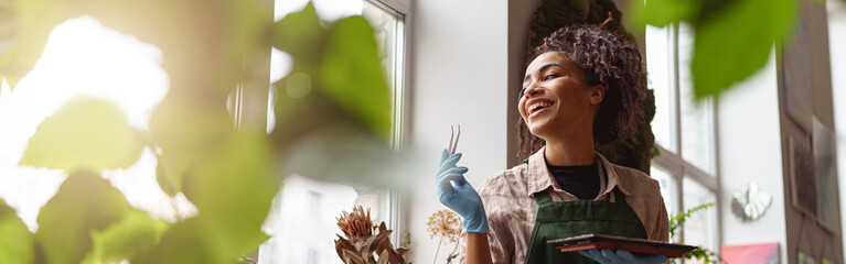 Woman florist takes care of seedlings in floral studio. Gardening concept. Blurred background