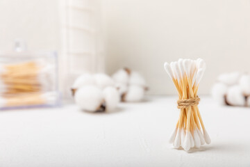 Cotton buds on a light concrete background.Eco-friendly materials. Wooden, cotton swabs on a white background.Bamboo swabs and cotton flowers.Zero waste, plastic free lifestyle concept.Place for text.