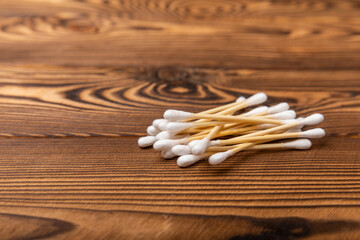 Fototapeta premium Cotton buds on a brown background.Eco-friendly materials. Wooden, cotton swabs on a white background.Bamboo swabs and cotton flowers.Zero waste, plastic free lifestyle concept.Place for text.