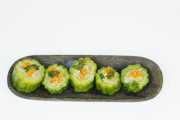 Pare or Bitter gourd stuffed with minced chicken meat served on the wooden plate.