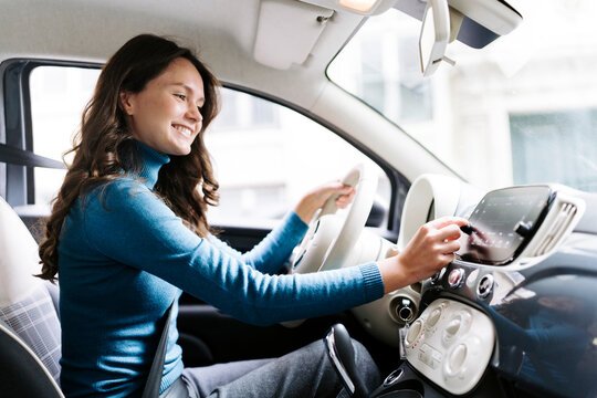 Smiling woman driving car and using dashboard