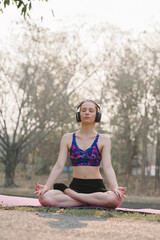 A beautiful sportswoman in sportswear is Practicing Breathing Exercise in Autumn city park...