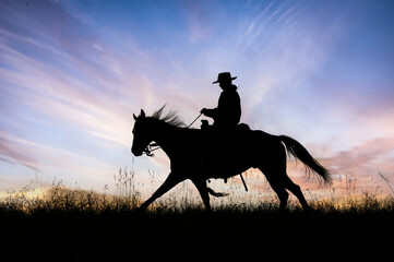 Cowboy on horseback at dawn silhouette