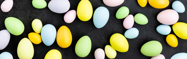 Stylish background with colorful easter eggs on dark concrete background with blooming branches of sakura flowers